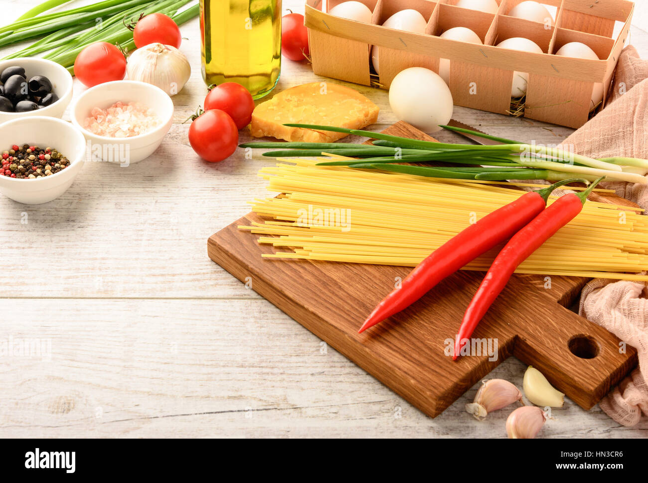 Ingredients for cooking healthy Italian food and cutting board on a white wooden table with space for an object in a home kitchen Stock Photo