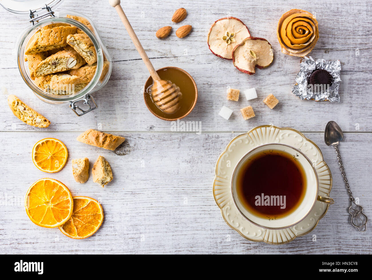 Tasty and healthy almond cookies, rich in vitamins, minerals in a glass jar, cup of tea, honey, almonds, chocolates, dried apples, dried lemons and su Stock Photo