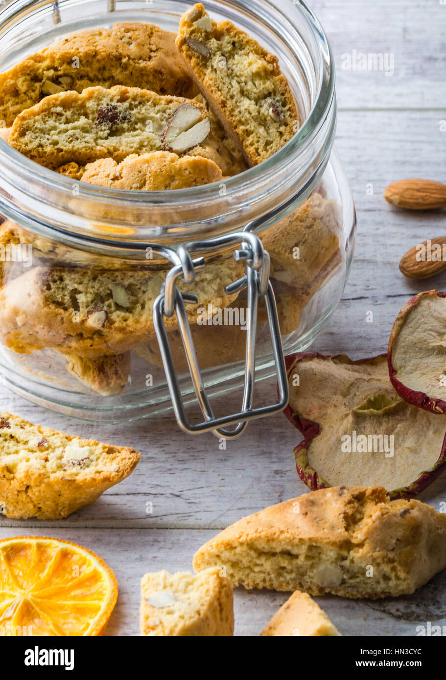 Tasty and healthy almond cookies, rich in vitamins, minerals in a glass jar and almonds and dried apples dried lemons on a white wooden table. Close u Stock Photo