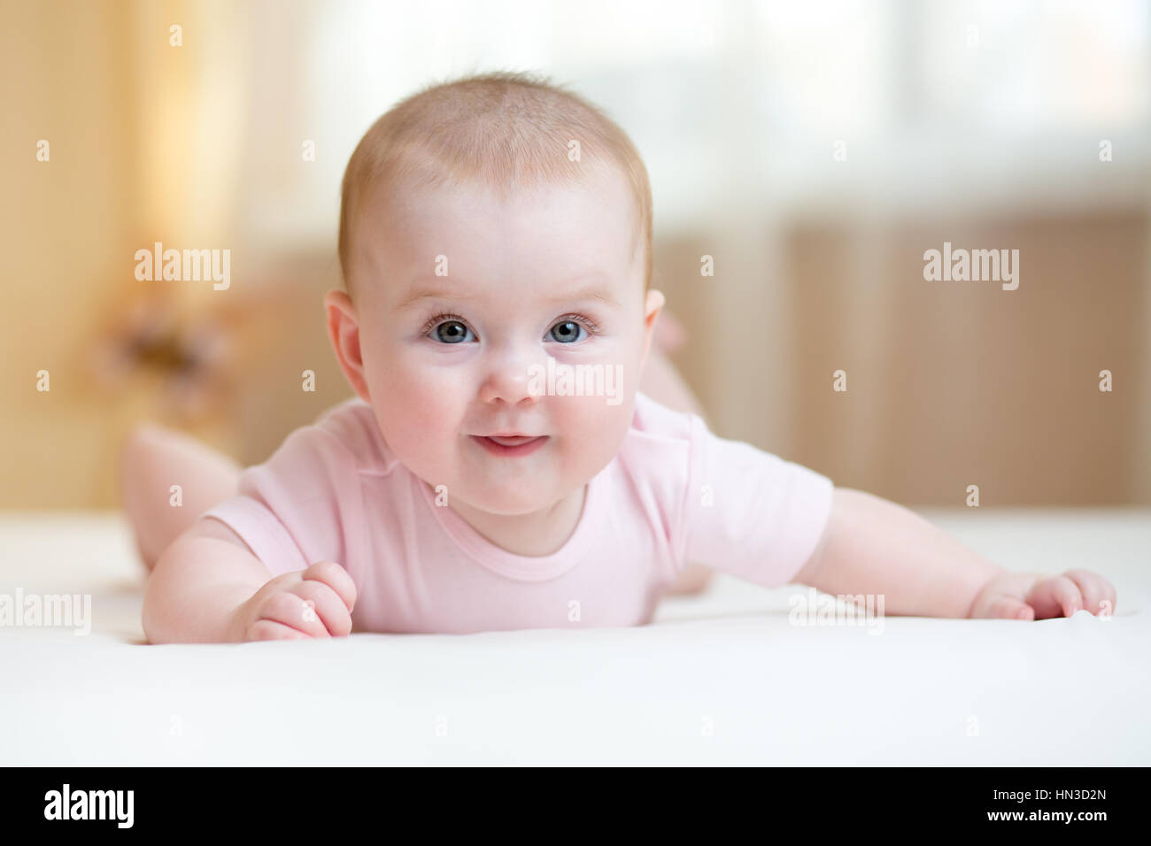 Cute baby wearing lying on tummy in bedroom Stock Photo