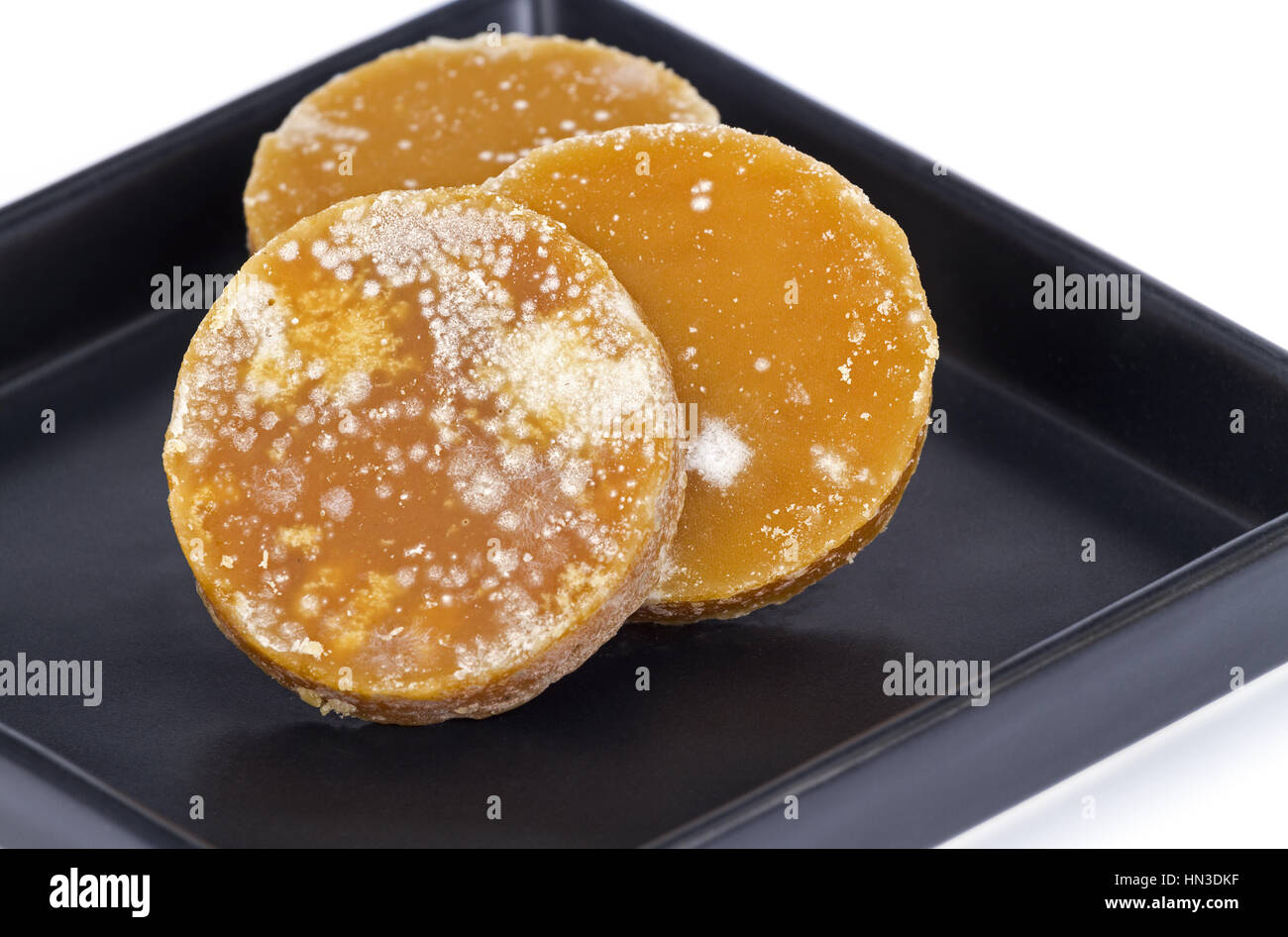 Traditional Sliced brown coconut sugar on black dish Stock Photo