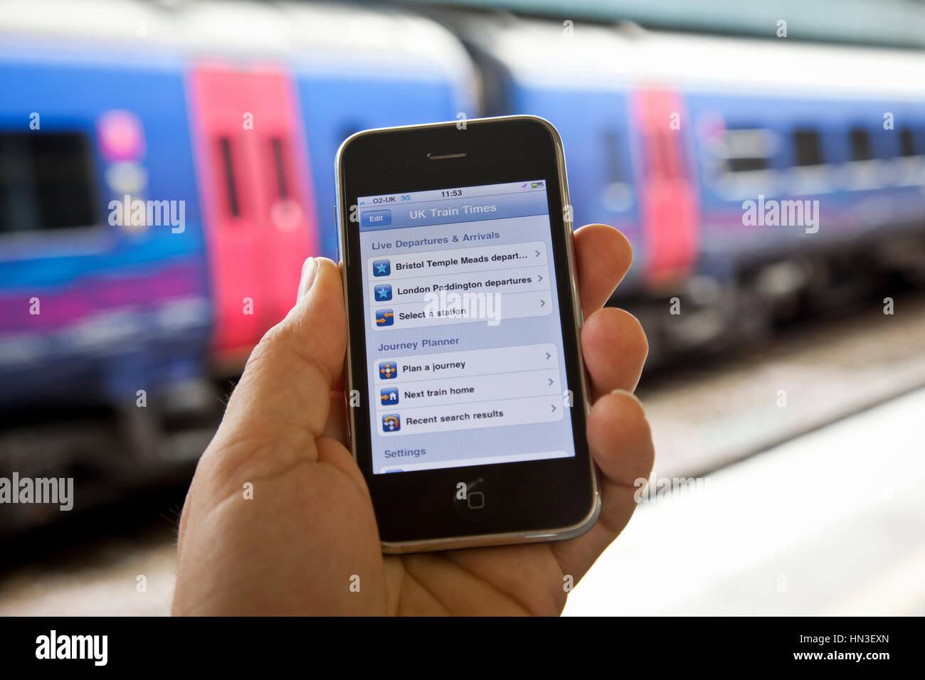 Bristol, United Kingdom - October 4, 2011: A male hand holding up an Apple iPhone 3Gs at Bristol Temple Meads station with train carriages out of focu Stock Photo