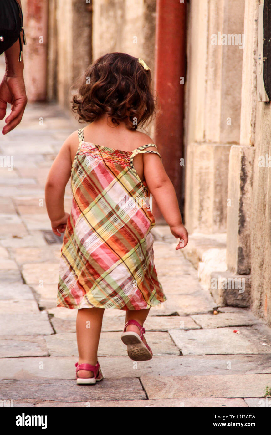 Young toddler walking on a cobbled street pavement Stock Photo