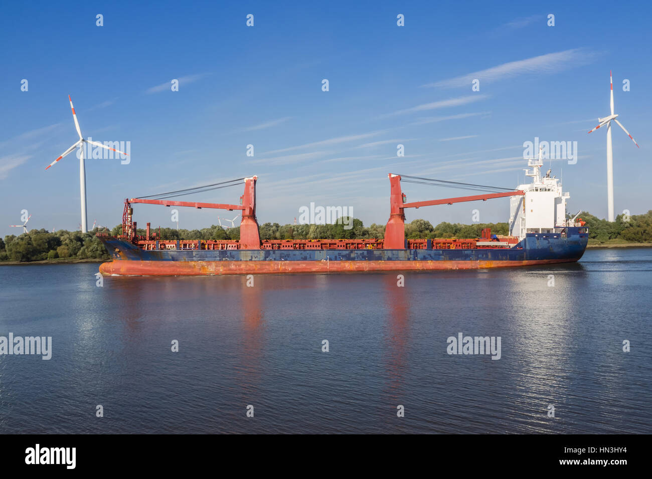 Freight ship on a river between two wind turbines Stock Photo