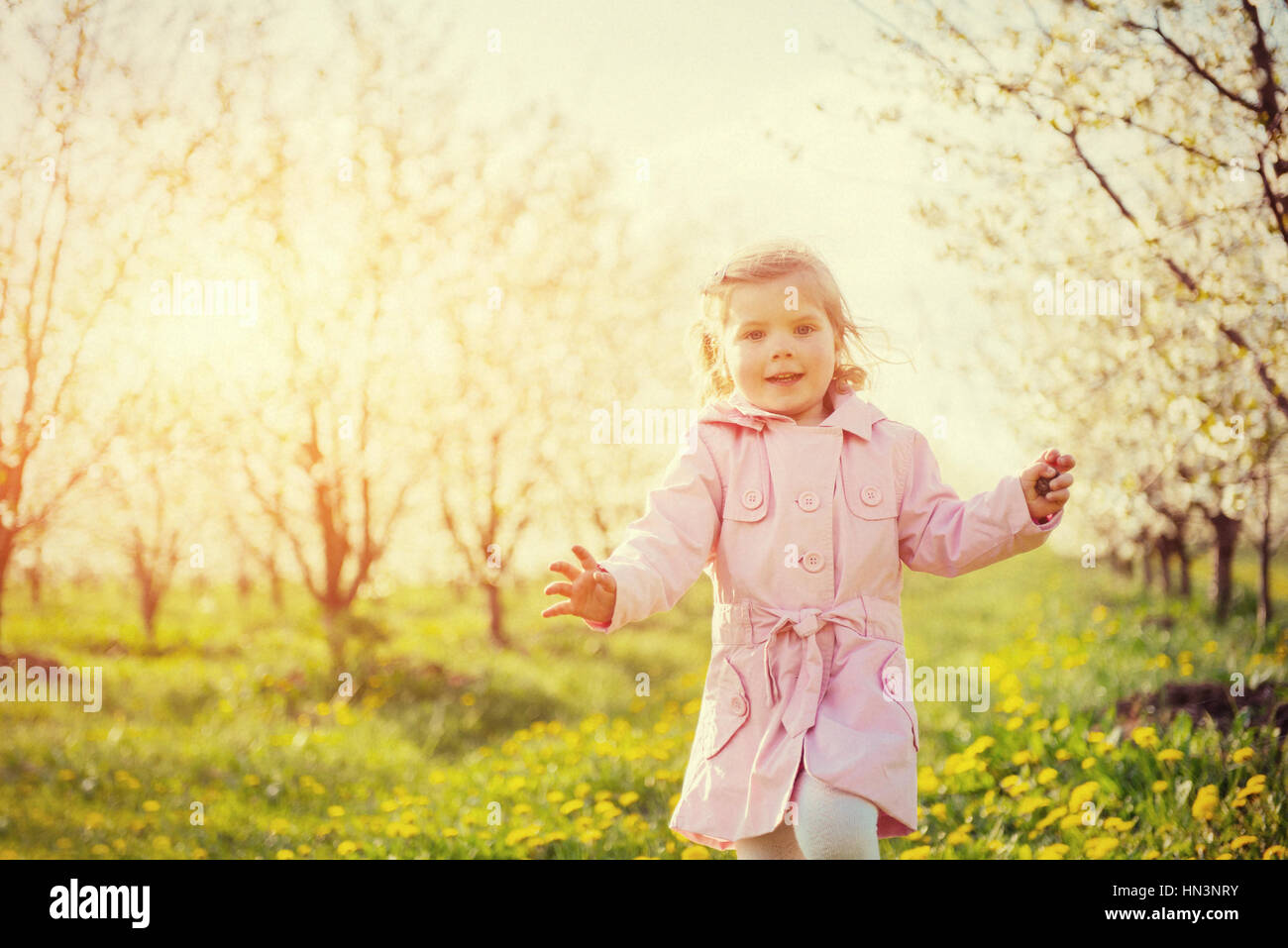 Child running outdoors blossom trees. Stock Photo