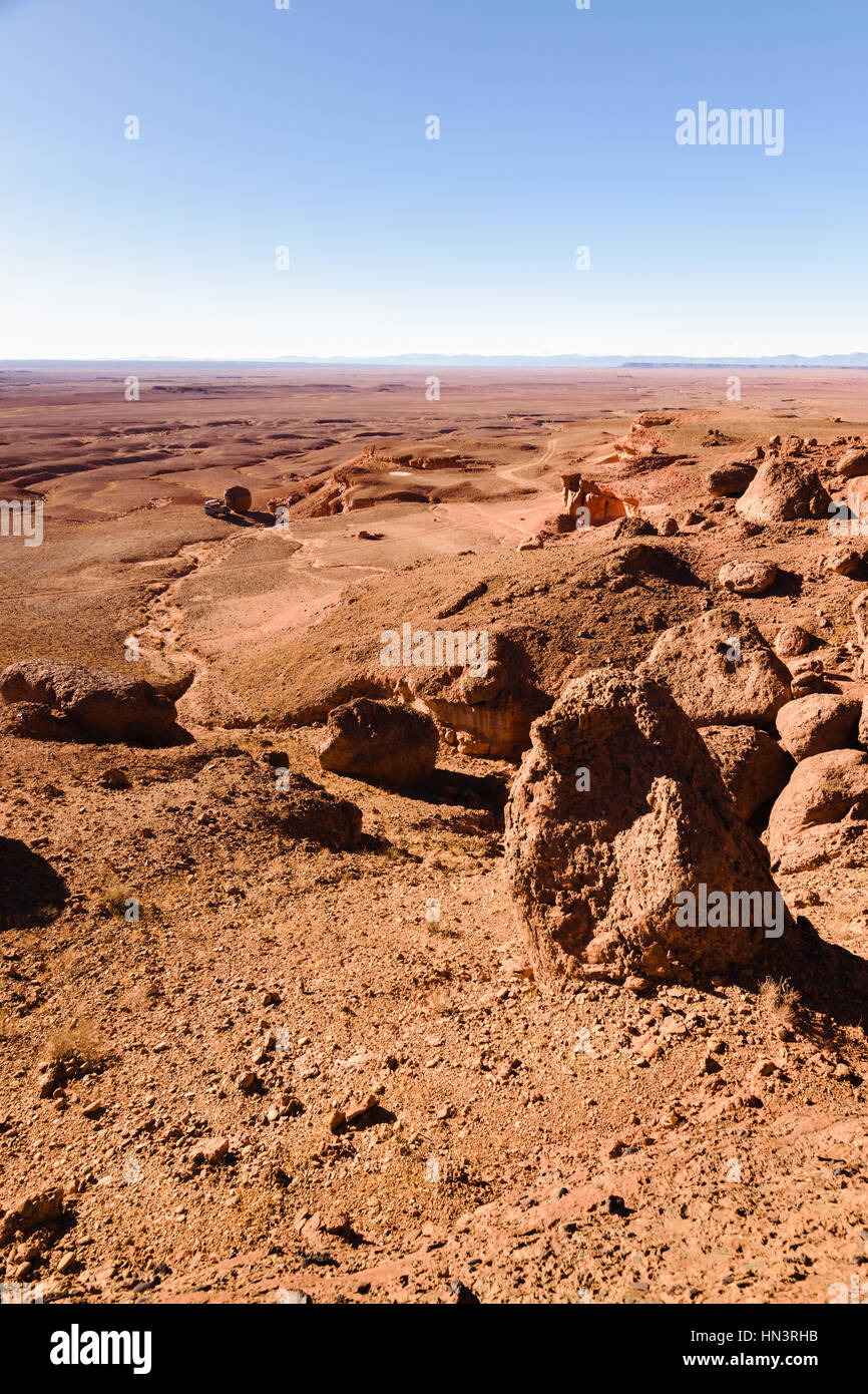 A four by four offroad oldtimer parking next to a big round stone in a stone desert in Moroco. Stock Photo