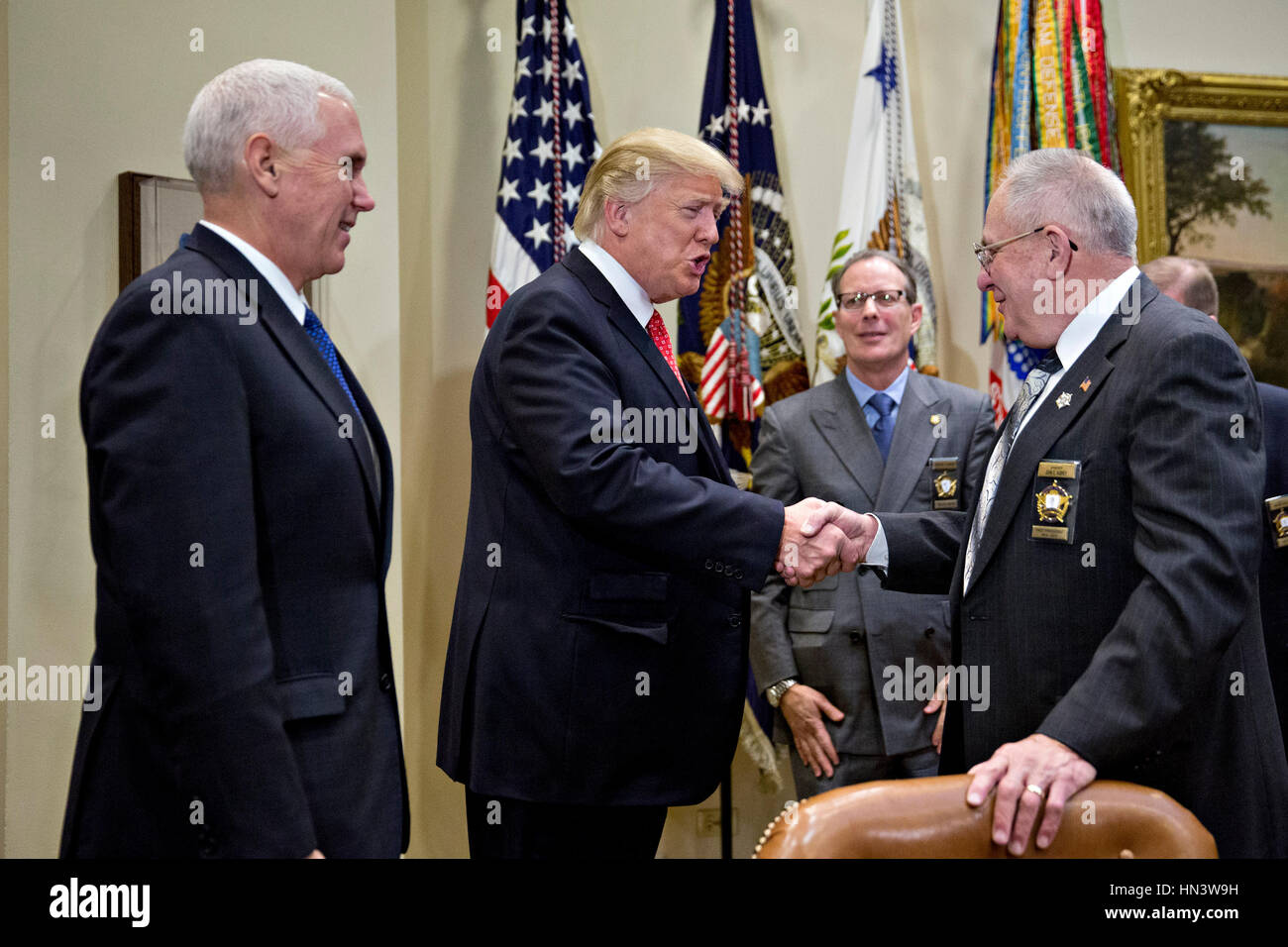 Washington DC, USA. 7th February 2017. U.S. President Donald Trump, center, shakes hands with John Aubrey, sheriff from Jefferson County, Kentucky, as he arrives with U.S. Vice President Mike Pence, left, for a listening session with county sheriffs in the Roosevelt Room of the White House in Washington, DC, U.S., on Tuesday, Feb. 7, 2017. The Trump administration will return to court Tuesday to argue it has broad authority over national security and to demand reinstatement of a travel ban on seven Muslim-majority countries that stranded refugees, triggered protests and handed the young govern Stock Photo