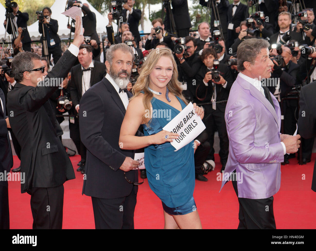 The cast of Expendables 3, Antonio Banderas, Mel Gibson, Ronda Rousey, and Sylvester Stallone, hold up Bring Back Our Girls signs  on the red carpet at the Cannes Film Festival on May 18, 2014, in Cannes, France.  Photo by Francis Specker Stock Photo