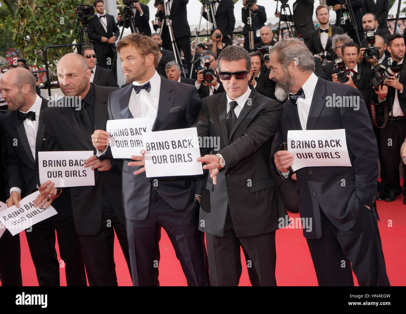 The cast of Expendables 3 Jason Stratham, Randy Couture, Kellan Lutz, Antonio Banderas, and Mel Gibson hold up Bring Back Our Girls signs  on the red carpet at the Cannes Film Festival on May 18, 2014, in Cannes, France.  Photo by Francis Specker Stock Photo