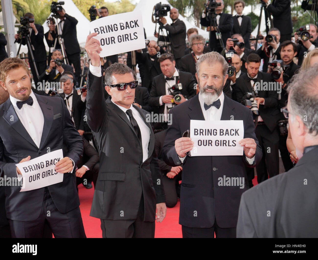 The cast of Expendables 3, Kellan Lutz, Antonio Banderas,  and Mel Gibson hold up Bring Back Our Girls signs  on the red carpet at the Cannes Film Festival on May 18, 2014, in Cannes, France.  Photo by Francis Specker Stock Photo
