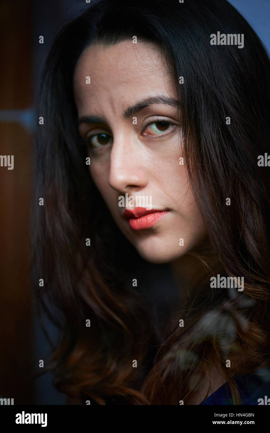 close up of sad young woman look through window Stock Photo