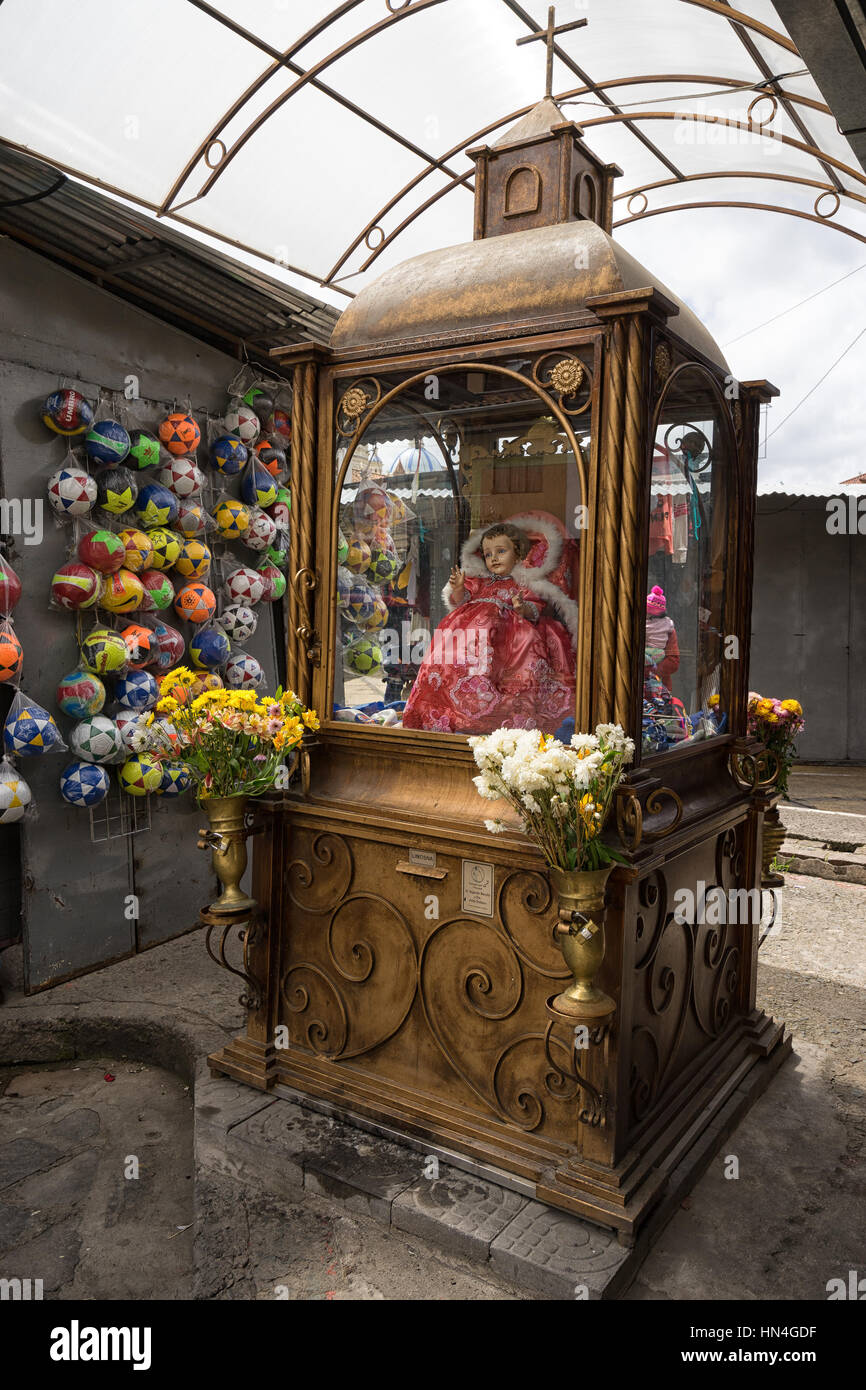 July 10, 2016 Cuenca, Ecuador: a small brass vintage religious monument n the artisan market with plastic balls hanging on the vendor's booth wall in Stock Photo