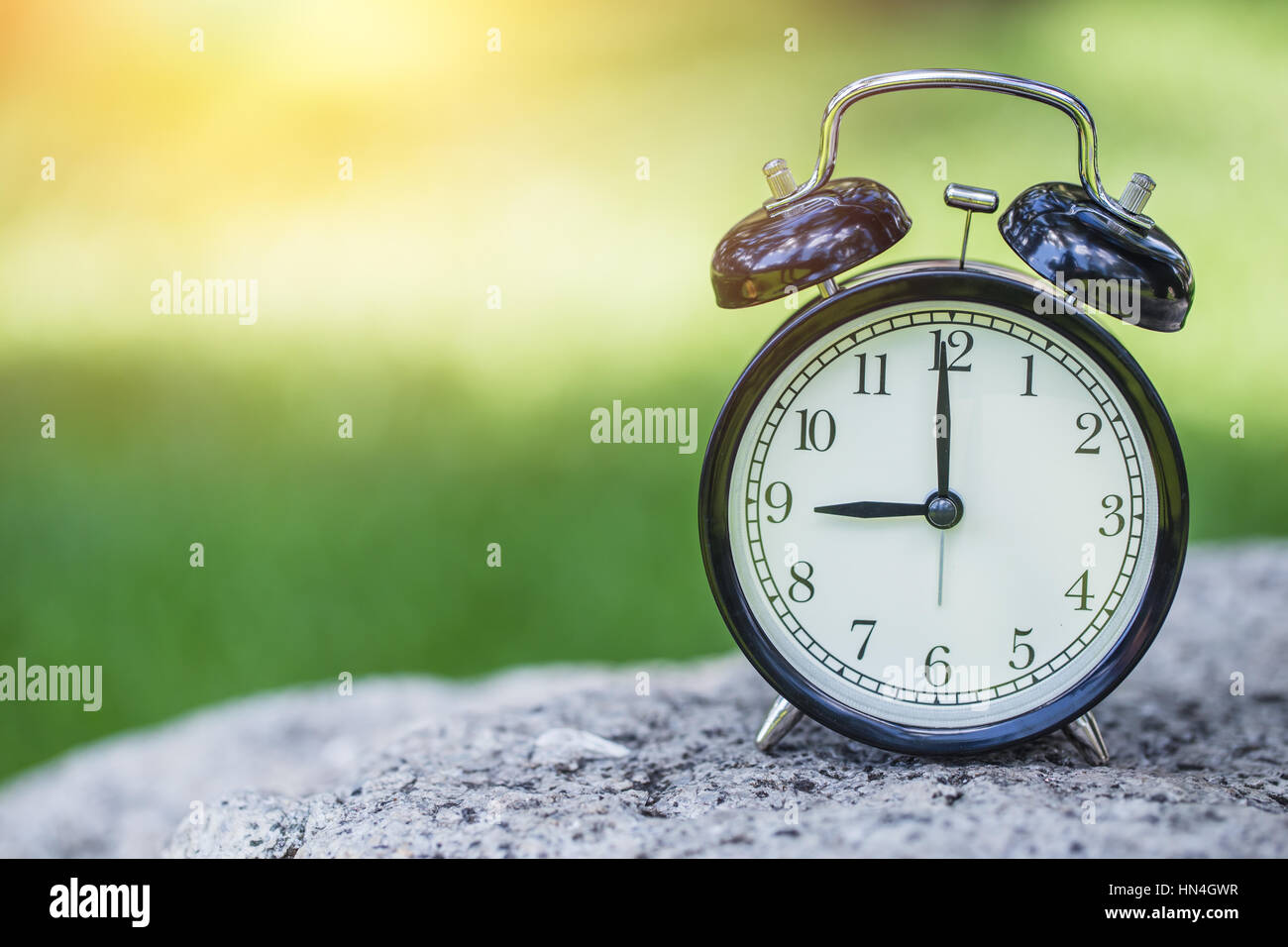 clock in the green nature background, retro bell clock time at 9 o