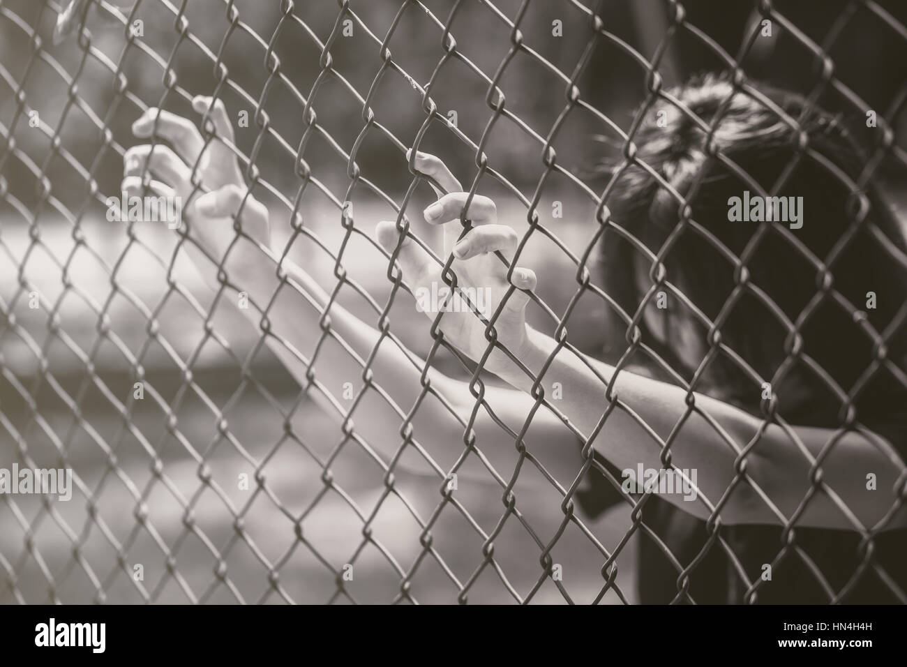 teen behide the cage or woman jailed, unhappy girl hand sad hopeless at fence prison in jail, no free and freedom struggle teen concept. Stock Photo