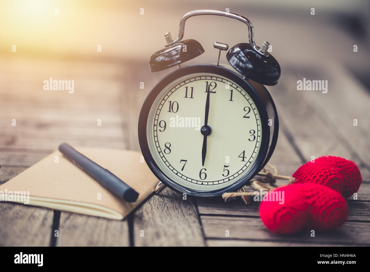 retro clock time at 6 o'clock with notebook or memo on wood table, times of love memory writing diary concept vintage color tone. Stock Photo