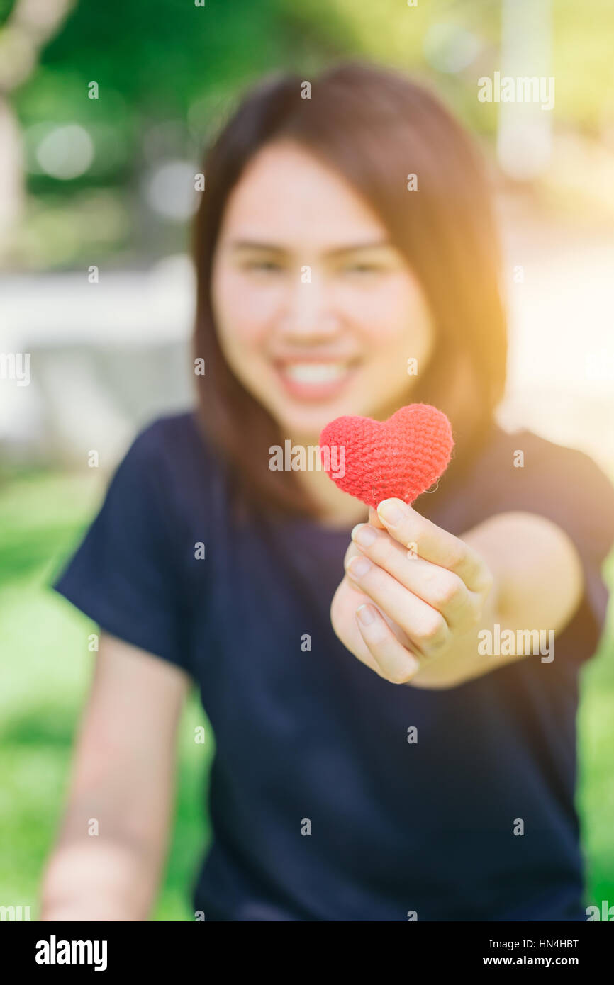 new friend love meeting and date cute smile Asian Thai teen hand hold red heart sweet loving symbol of take care or charity help to you. Stock Photo