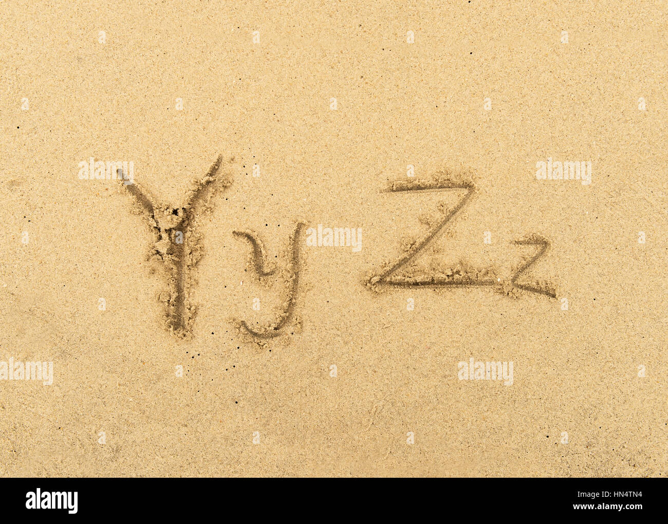 alphabet letters handwritten in sand on beach Stock Photo