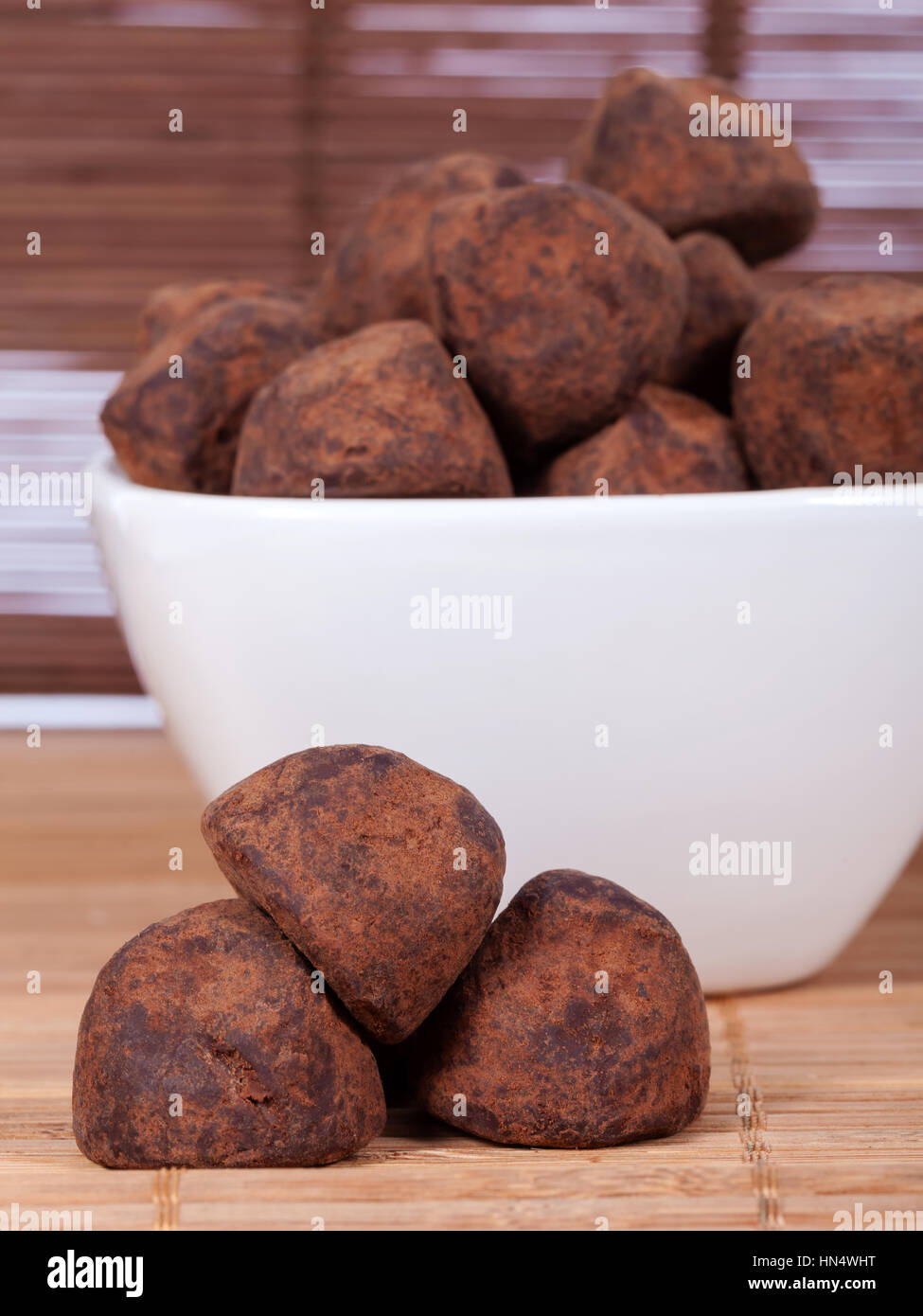 Black chocolate truffles in a white bowl covered with cinnamon powder Stock Photo