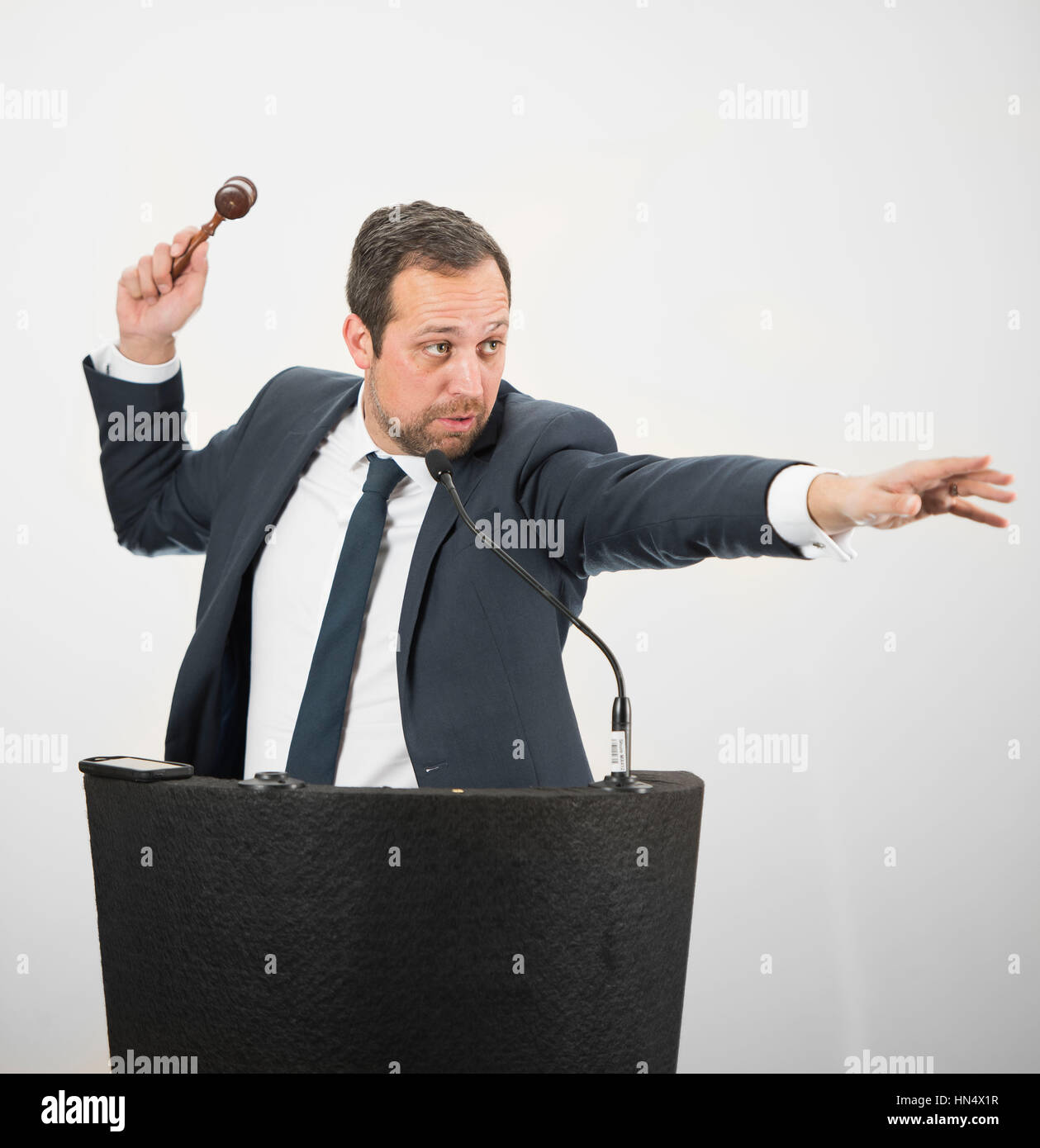A male auctioneer in action holing a gavel during a live auction Stock
