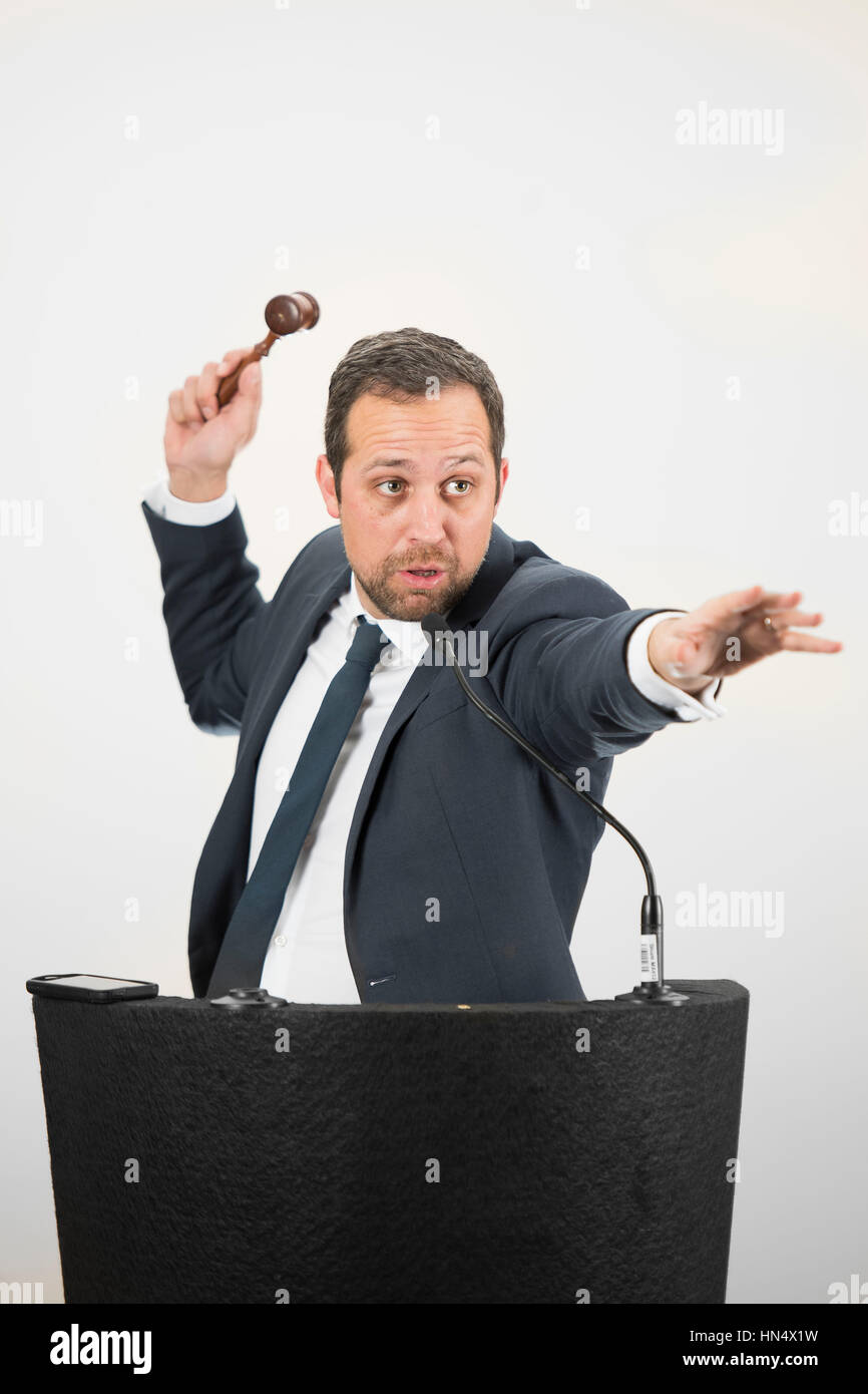 A male auctioneer in action holing a gavel during a live auction. Stock Photo
