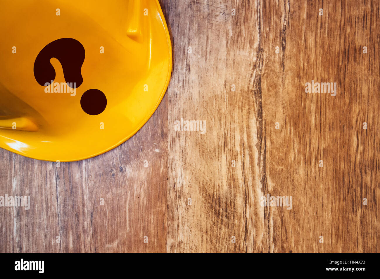 Protective yellow construction helmet with question mark on wooden table, top view Stock Photo