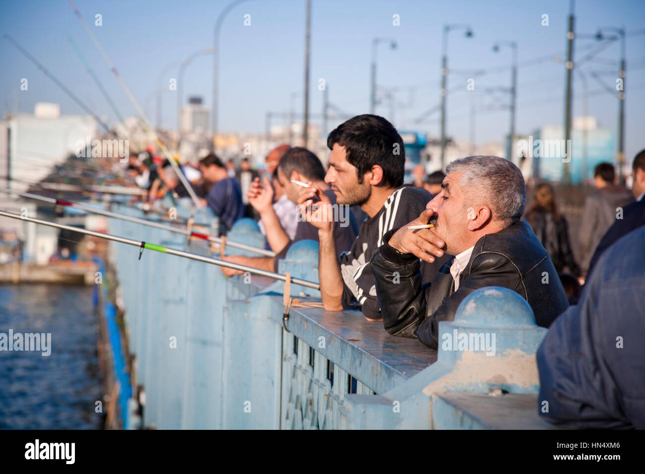 ISTANBUL, TURKEY - NOVEMBER 6 : A row of men smoking and fishing on the Galata Bridge in Istanbul, Turkey on 6th November 2009. The historic bridge sp Stock Photo