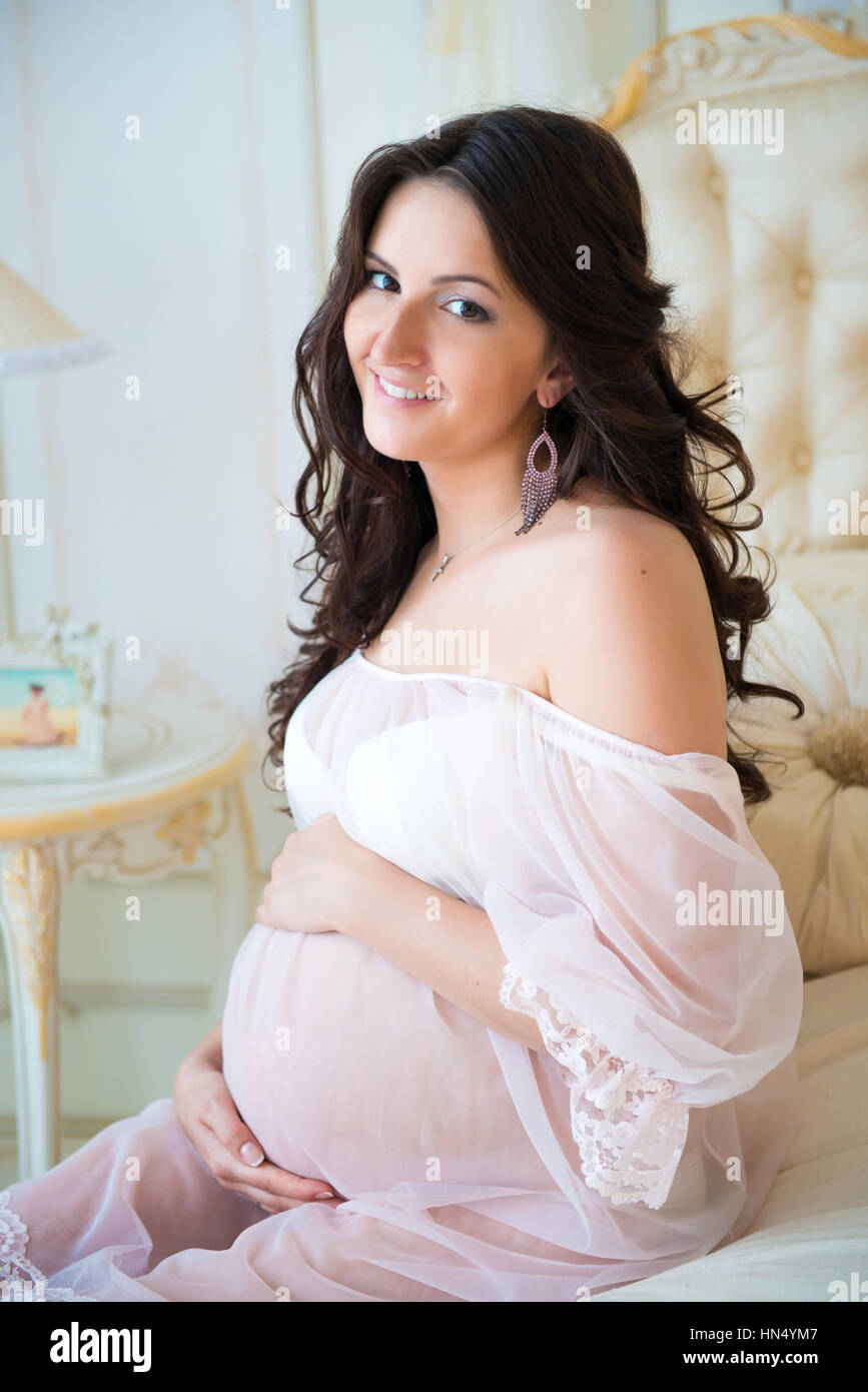 Beautiful Pregnant Girl In A Lace Negligee Sitting On A Bed Of Roses