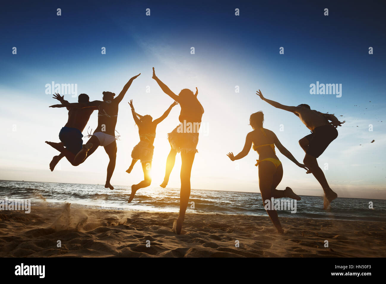 Happy friends sunset jump friendship holidays Stock Photo - Alamy