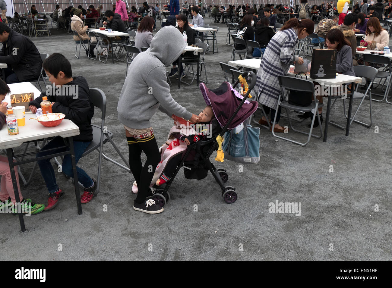 Japanese people, families, tourists eating traditional Asian street food at city fair. Hiroshima, Japan, Asia Stock Photo