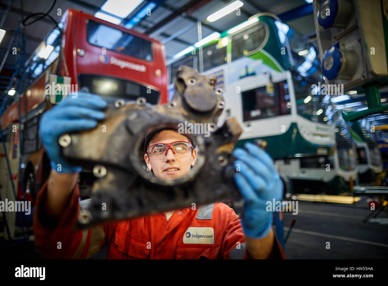 A young teenage apprentice fitter mechanic fixing broken down double decker bus engine at Stagecoach bus operators Wythenshawe depot in Manchester, En Stock Photo