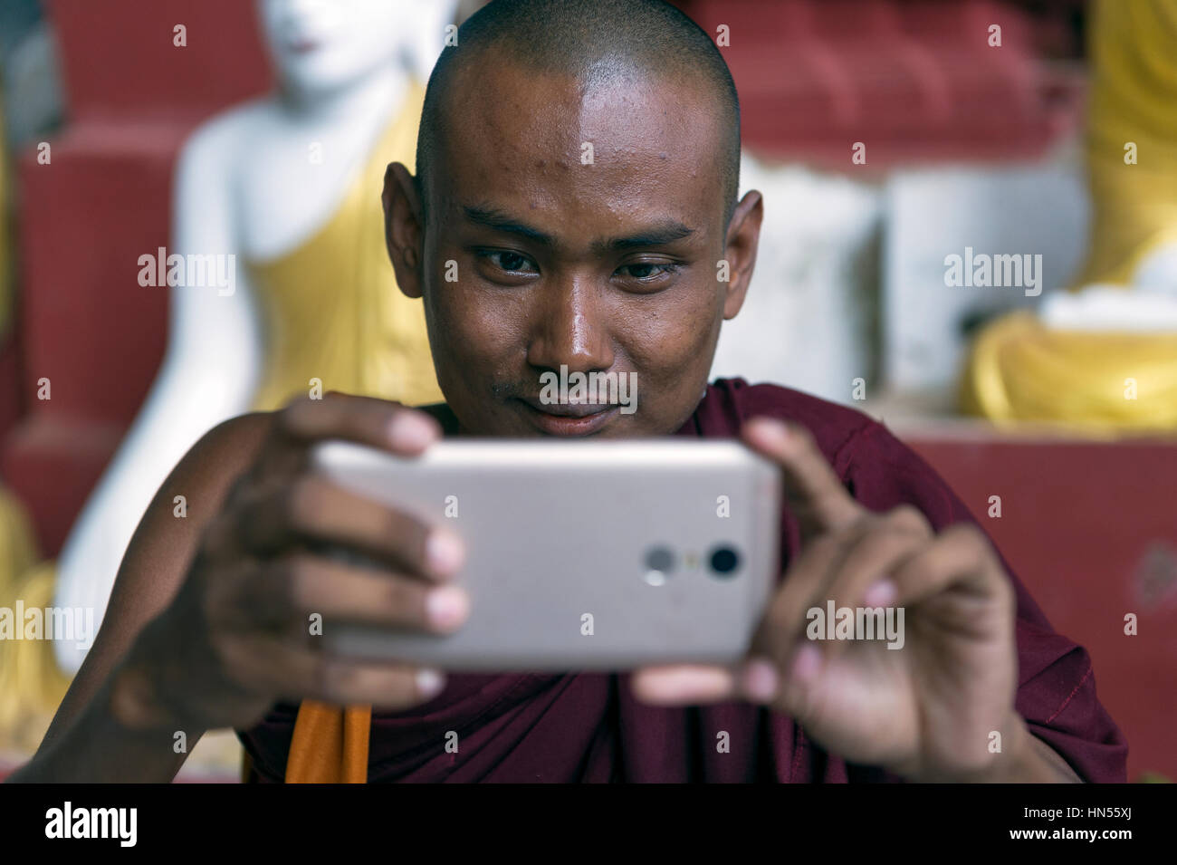 Myanmar (formerly Burma). Kayin State (Karen State). Hpa An. Kaw Gon (Kaw Goon) cave, dated 7th century. Young monk taking pictures with a smartphone Stock Photo