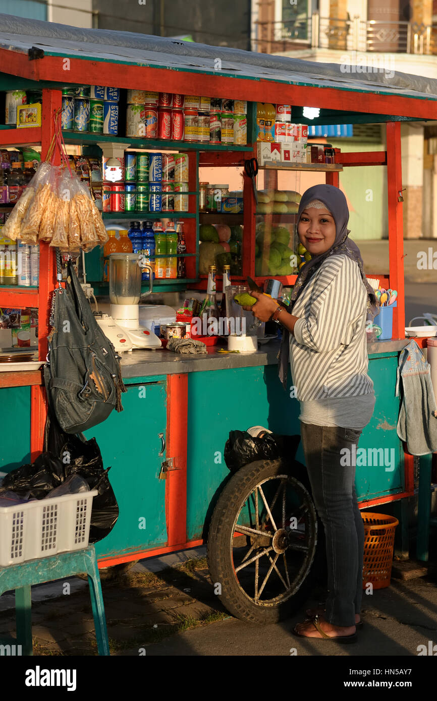 BERAU, BORNEO, INDONESIA - JUNE 24: Resident of the industrial Berau city on an island Borneo in Indonesia is standing in front of the stall Stock Photo