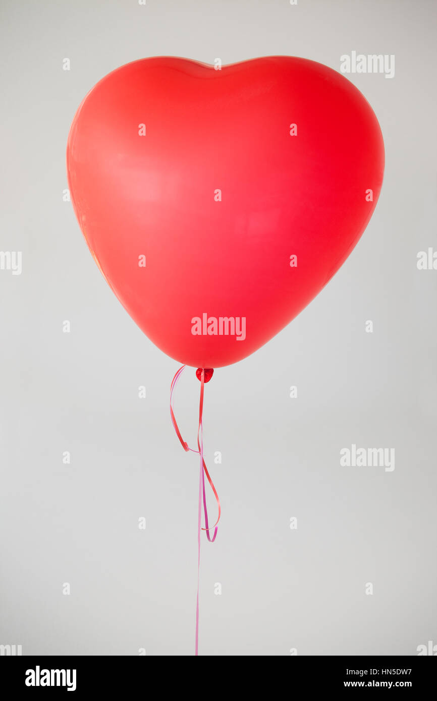 Heart-shaped red balloon against white background Stock Photo - Alamy