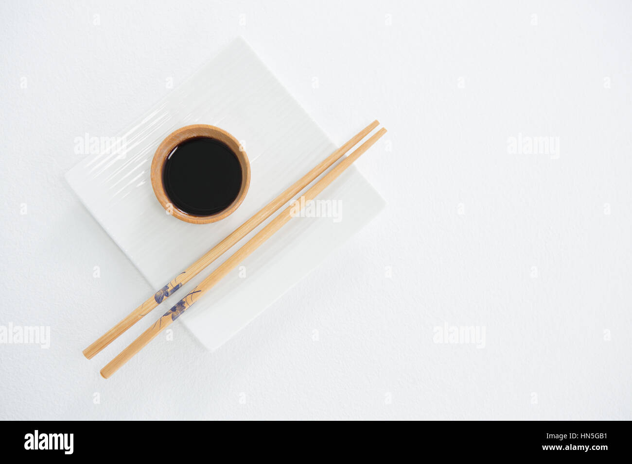 Chopstick and soy sauce on white plate against white background Stock Photo