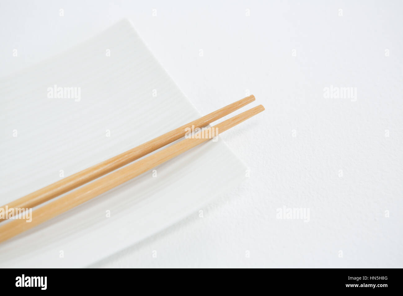 Chopstick with empty plate against white background Stock Photo