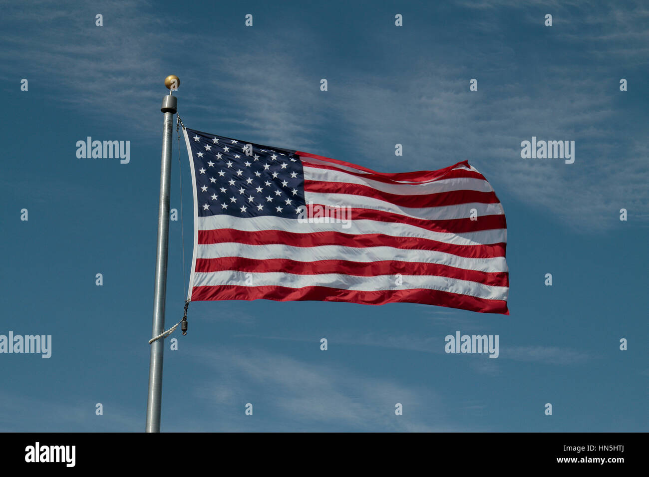 The Star Spangled Banner flying against a blue sky background. Stock Photo