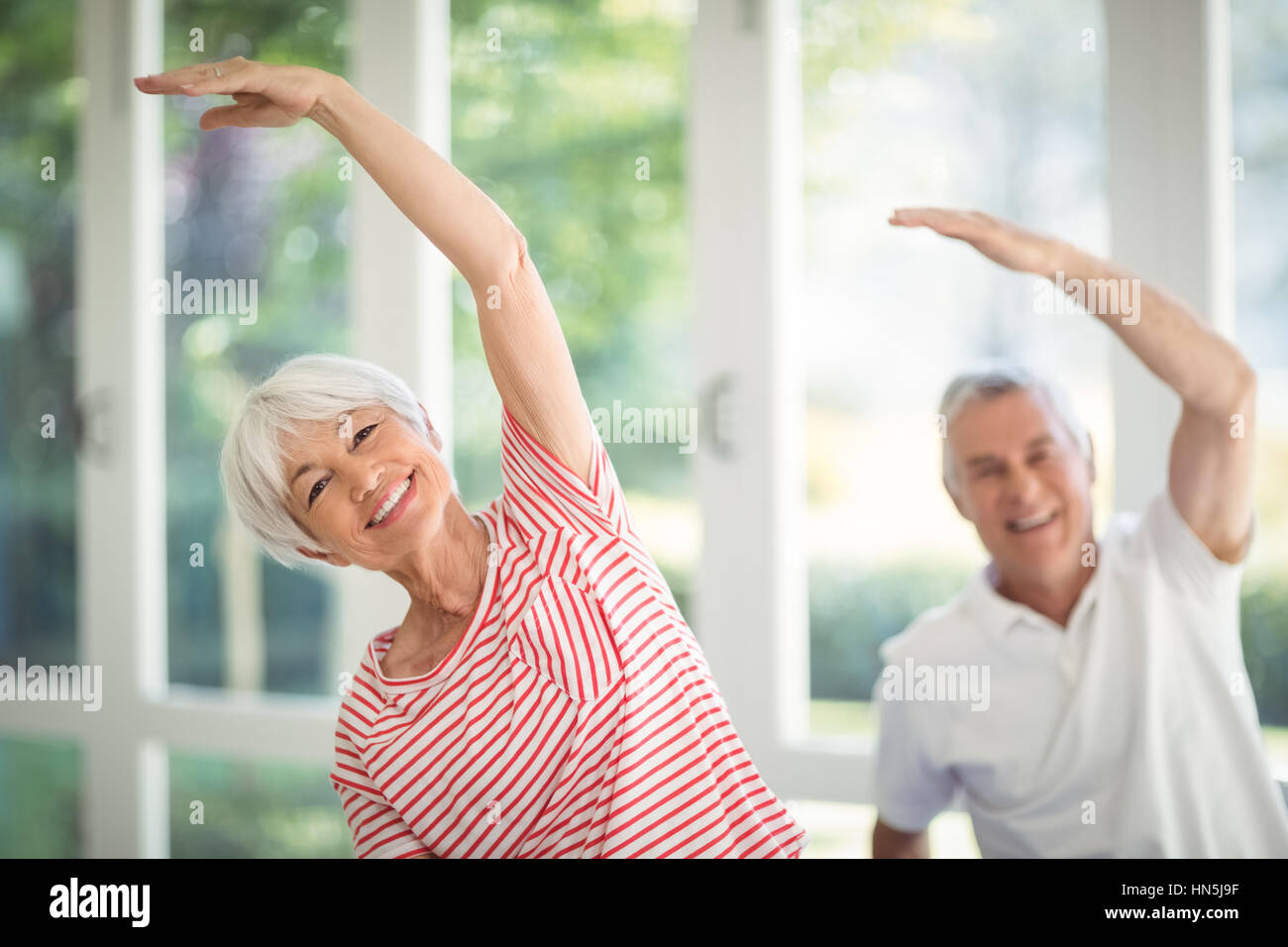 Happy senior couple performing stretching exercise at home Stock Photo ...
