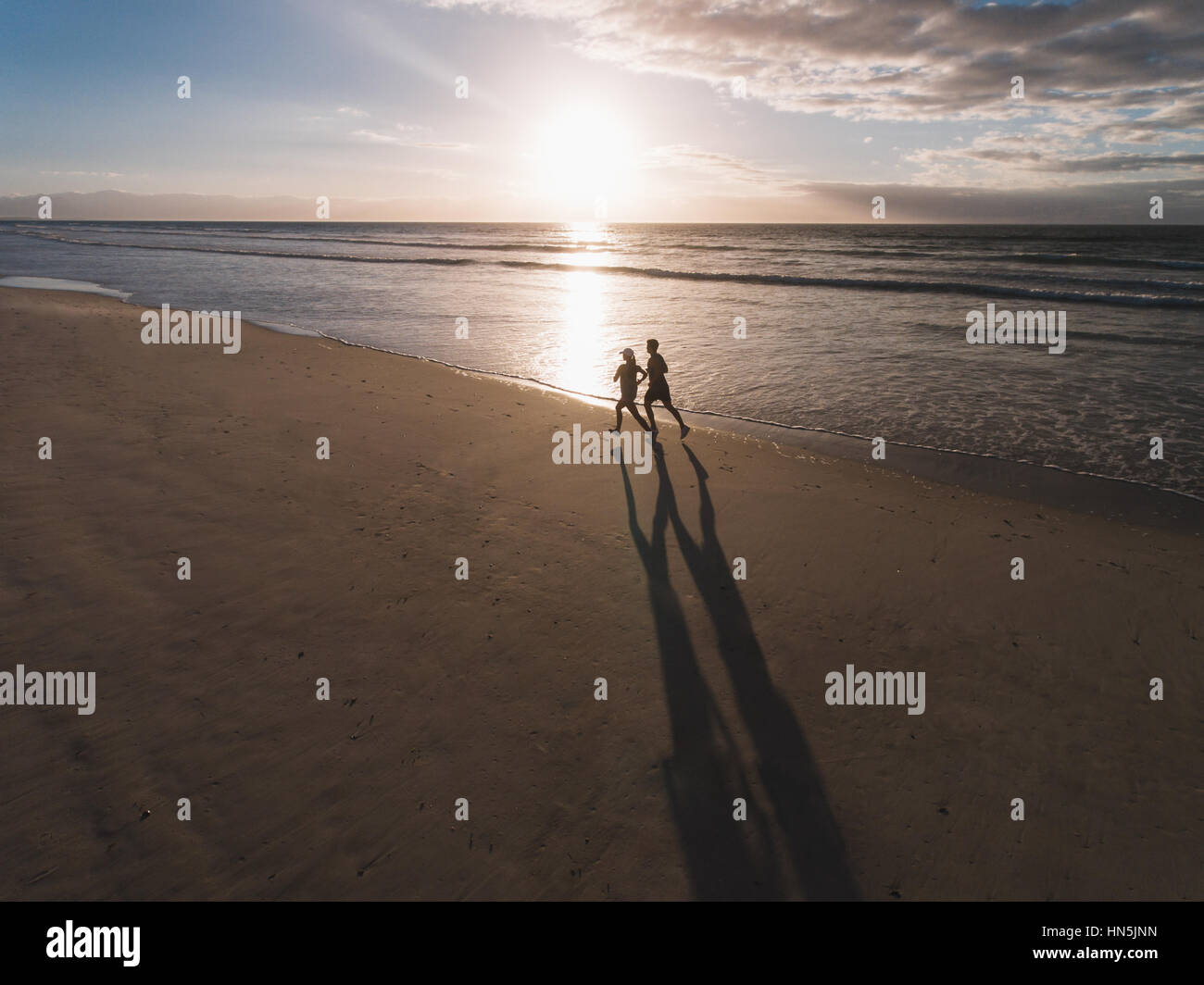 Beautiful beach with couple of runner running on the shore. People on ...