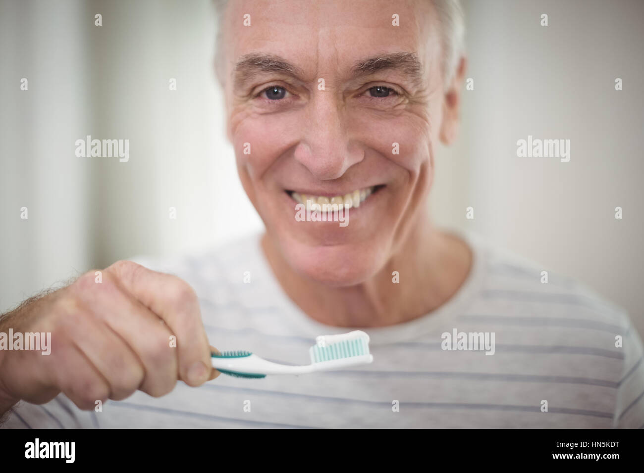 Portrait of senior man brushing his teeth in bathroom at home Stock Photo