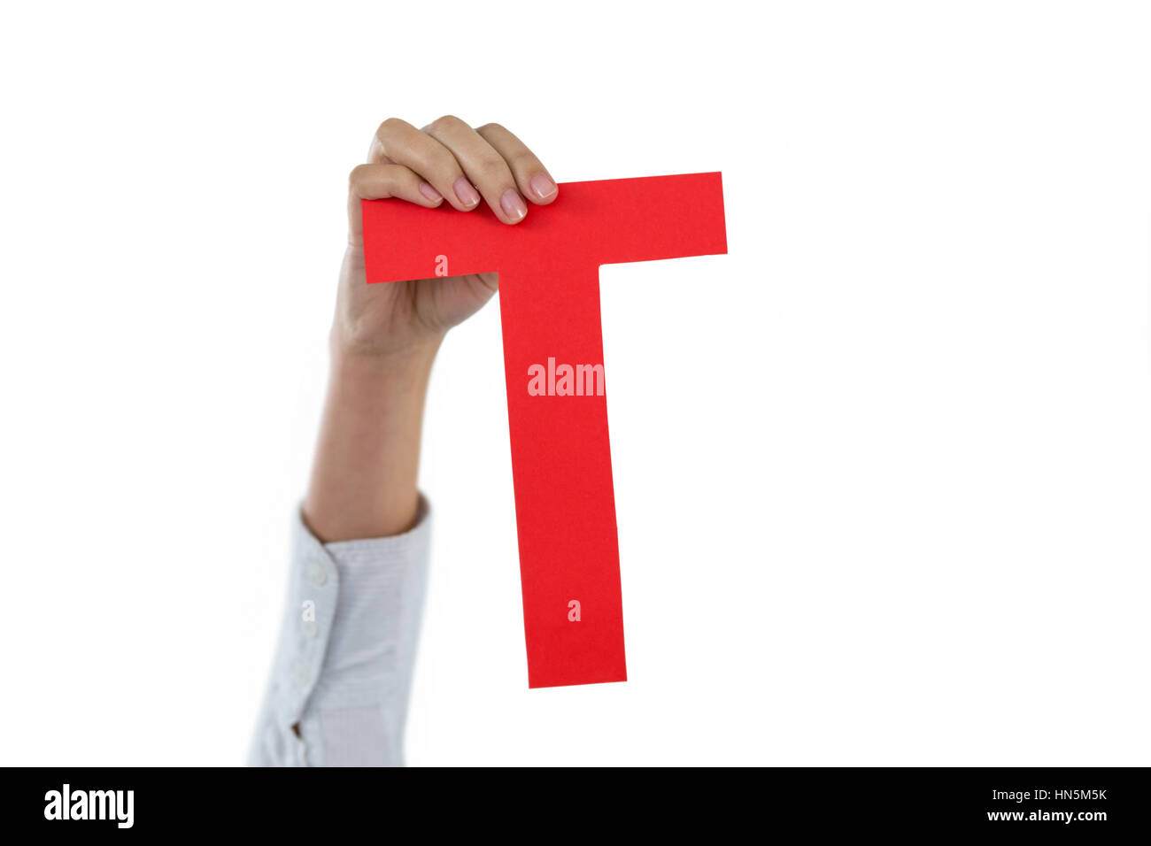 Hand of businesswoman holding alphabet t against white background Stock Photo