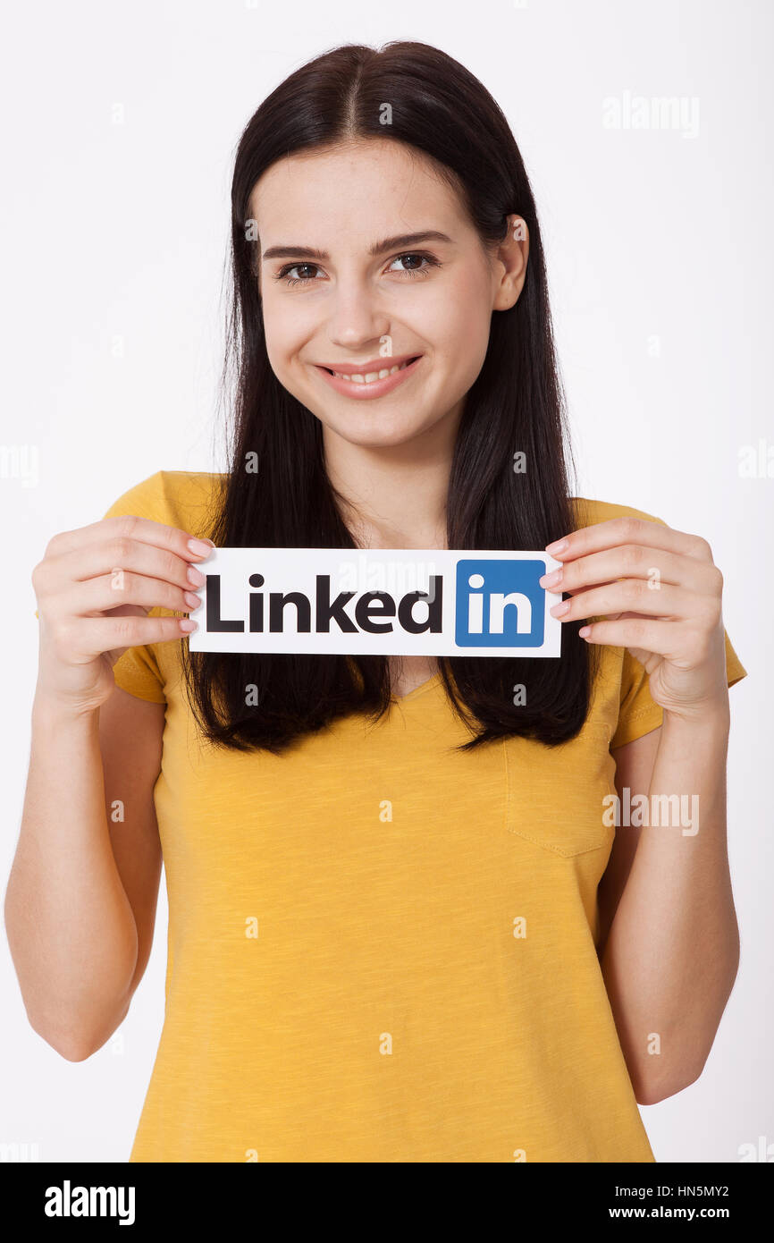 KIEV, UKRAINE - August 22, 2016: Woman hands holding Linkedin logo sign printed on paper on white background. Linkedin is business social networking service. Stock Photo