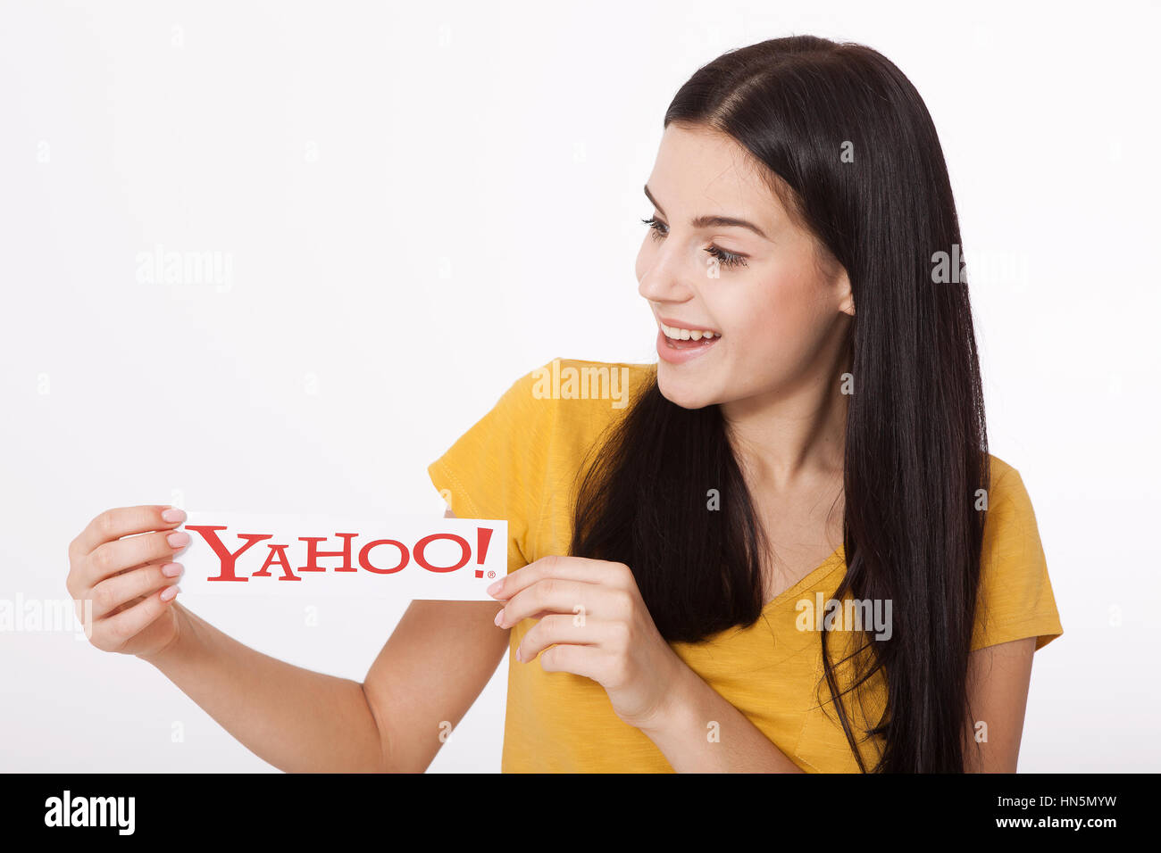 Kiev, Ukraine - August 22, 2016: Woman hands holding the logo of the brand Yahoo icons printed on paper on grey background. Stock Photo