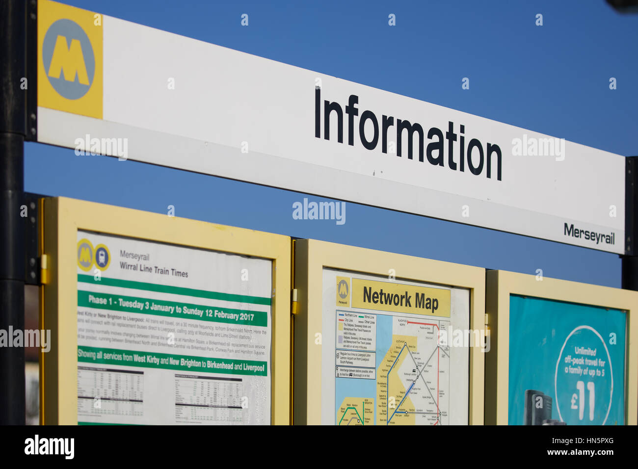 Blue sky on a sunny day Merseyrail commuter rail network M logo on information timetable boards and station sign in  Wallasey, Merseyside, Wirral, Eng Stock Photo