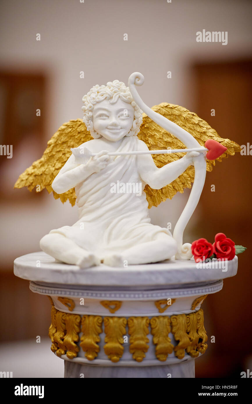 Cupid by Cake designer to the stars  Rosie Cake Diva by Rose Dummer  with a valentines day creation with Cupid God of desire, Stock Photo