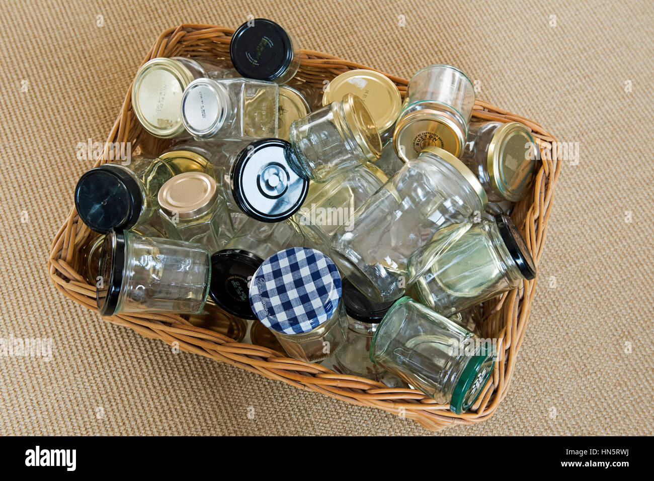 Empty glass jars with lids in wicker basket washed and ready for reuse, storage or recycling. Stock Photo