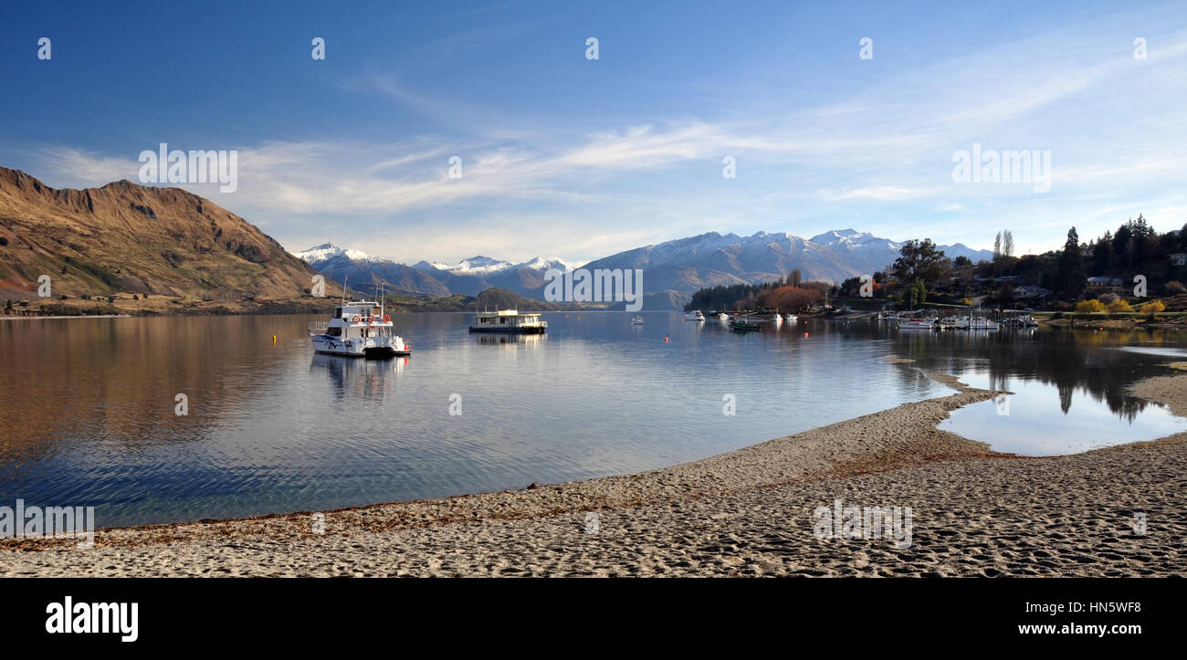 Lake Wanaka and boats with the Southern Alps in the background. Central Otago, New Zealand. In the foreground note how low the lake level is after one Stock Photo
