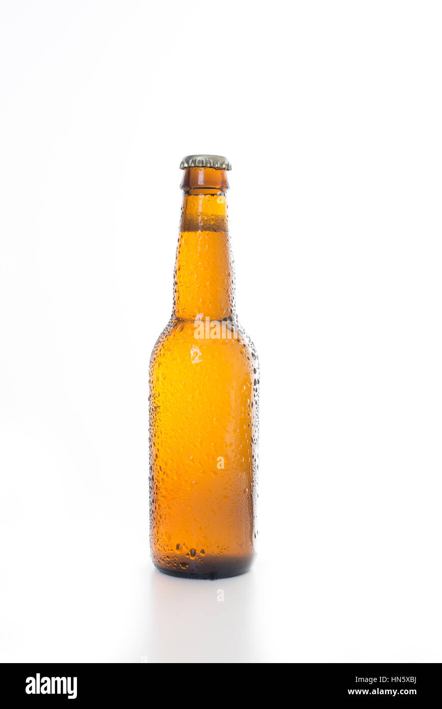 Single brown beer bottle with condensation set against a white background. Stock Photo