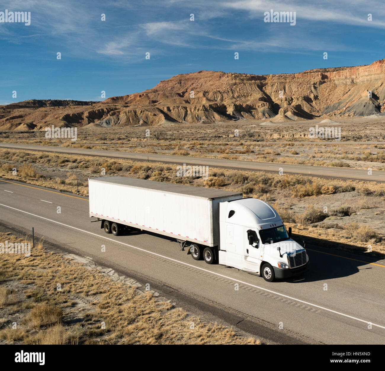 A white big rig rolls across Utah on a divided highway Stock Photo