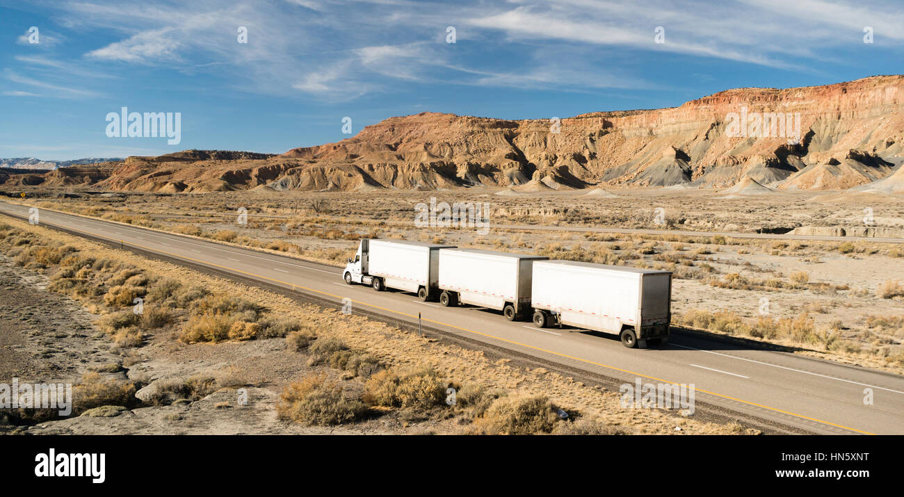 A Semi Truck carrying three tandem trailers over the road Stock Photo