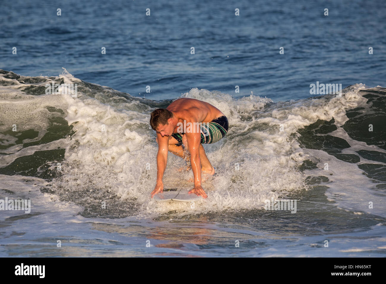 A young man in his early 20's surfing. He has caught a wave in the Atlantic Ocean. The location is the New Jersey Shore. Stock Photo